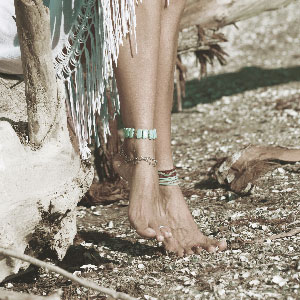 Feet wearing beach chic anklets.