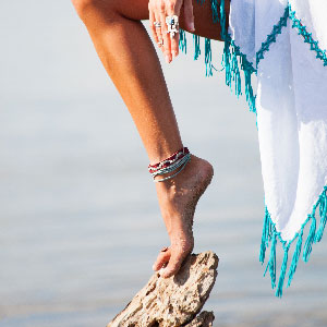 Woman's foot on a rock wearing turquoise anklets.