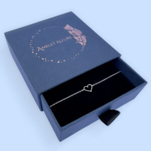 Sterling silver anklet with a simple hollow heart charm, presented in a blue jewellery box with Anklet Allure written on the top in rose gold.