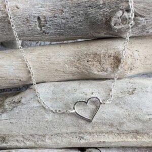 Outline of a heart pendant on a sterling silver ankle bracelet.