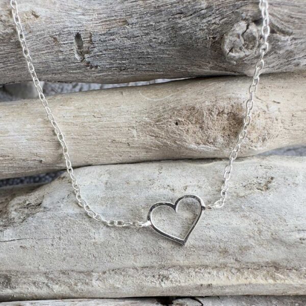 Outline of a heart pendant on a sterling silver ankle bracelet.