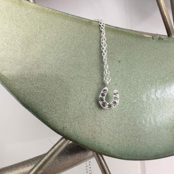 Horseshoe charm anklet on a light green metal background.