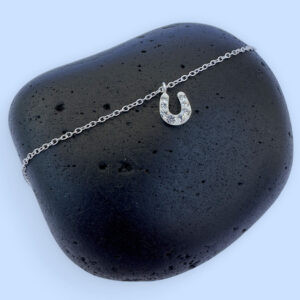 Sterling silver ankle bracelet with a horseshoe charm with white gems.