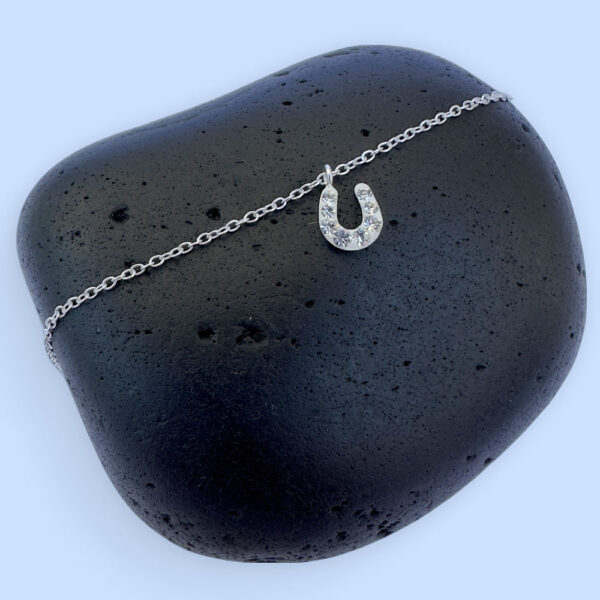 Sterling silver ankle bracelet with a horseshoe charm with white gems.