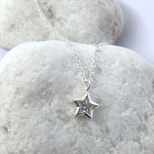 Close up of an anklet with a star charm with a white gemstone in the centre.