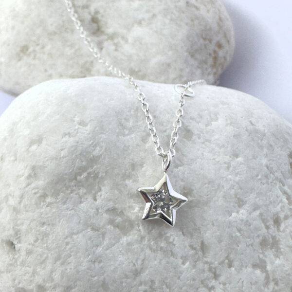 Close up of an anklet with a star charm with a white gemstone in the centre.