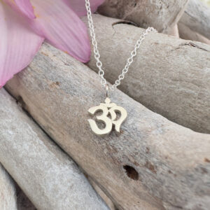 Ohm symbol charm on a sterling silver anklet displayed on wood.