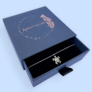 Tranquil anklet with a charm of a cute silver turtle, presented in a blue jewellery box with Anklet Allure written on the top in rose gold.
