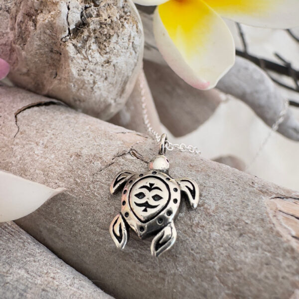 Beach chic anklet with a solid silver cute turtle pendant sitting on a piece of driftwood.