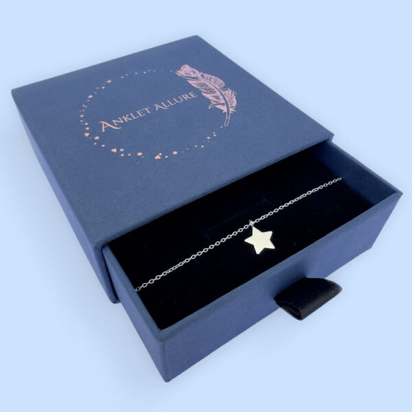 Shiny bright anklet with solid silver star charm, presented in a blue jewellery box with Anklet Allure written on the top in rose gold.