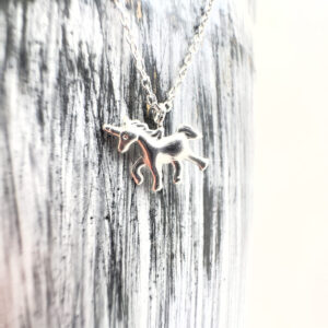 Cute unicorn charm on a silver anklet on a black and white background.