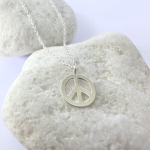 Peace symbol charm on a silver anklet.