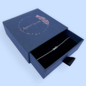 Sterling silver anklet with infinity charm, presented in a blue jewellery box with Anklet Allure written on the top in rose gold.