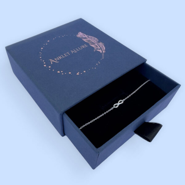 Sterling silver anklet with infinity charm, presented in a blue jewellery box with Anklet Allure written on the top in rose gold.