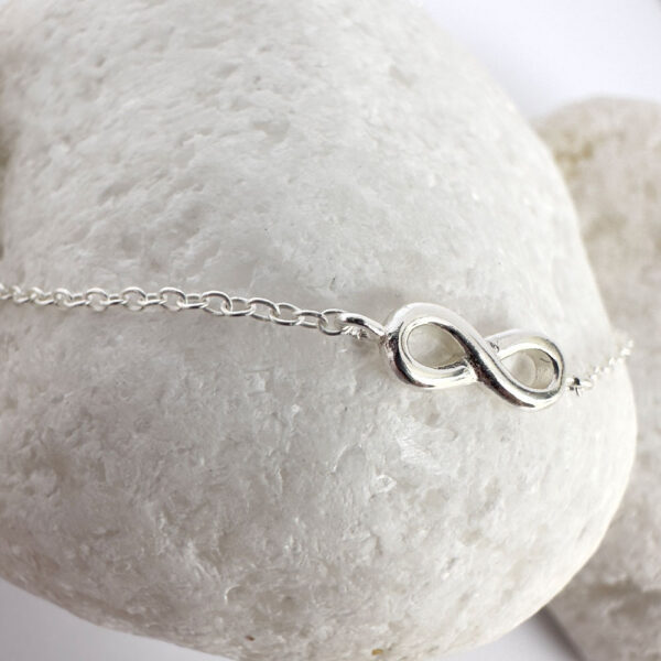 Close up of beautiful anklet with a chunky sterling silver infinity charm.