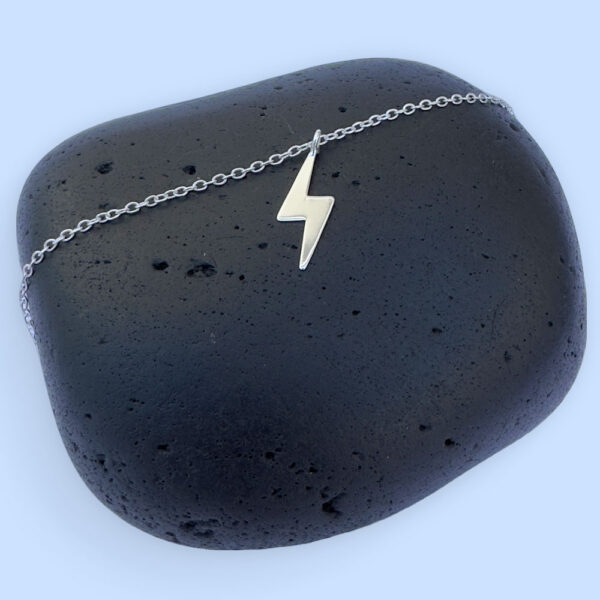 Powerful silver anklet with a charm of a lightening bolt.