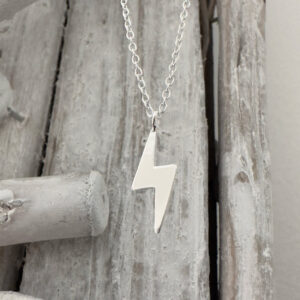 Anklet in 925 sterling silver with a shiny silver lightning bolt pendant hanging from a wood background.