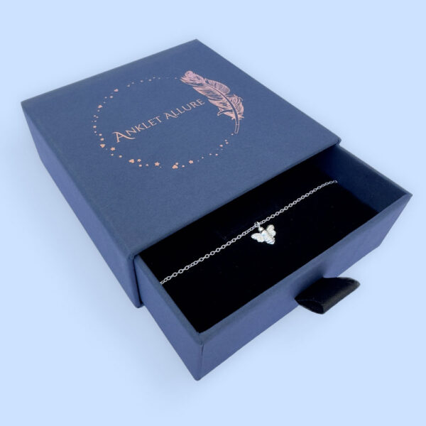 Silver anklet with charm attached of a bee, presented in a blue jewellery box with Anklet Allure written on the top in rose gold.