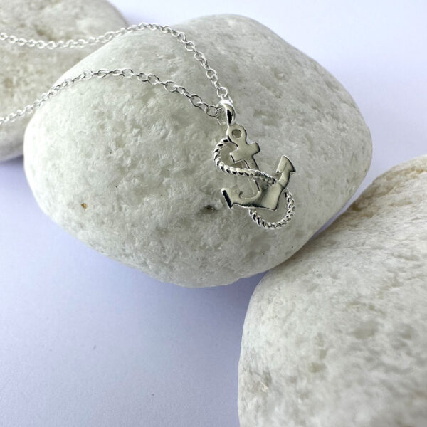 Silver adventurous anklet with a charm of an anchor with a rope wrapped around it in an s shape.