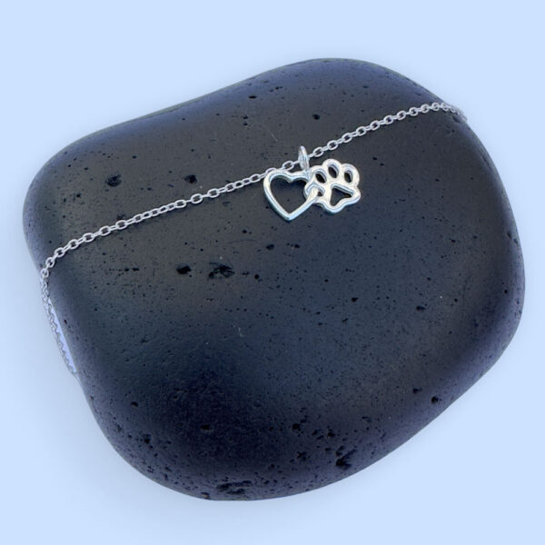 Silver anklet of a linked heart and pawprint.