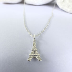 Close up of an elegant Parisien chic anklet in silver with a pendant of the Eiffel Tower.