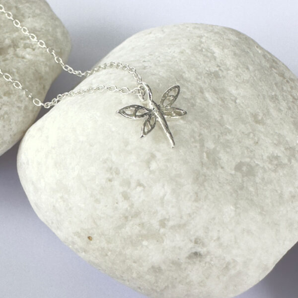 Close up of silver captivating anklet with a silver dragonfly charm.
