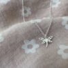 Beautiful dragonfly charm on a sterling silver ankle bracelet on a pink and white daisy fabric.