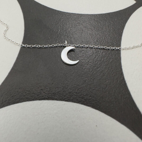 Sterling silver anklet with silver crescent moon charm on a black and white background.