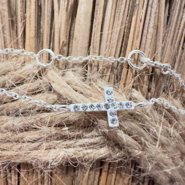 Silver anklet with 12 white gemstones on top sitting on a rope and straw background.