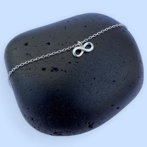 Close up of a stunning silver ankle bracelet with a beautiful infinity charm.