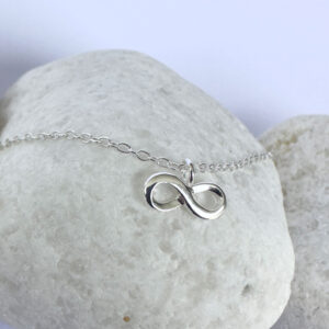 Close up of a silver anklet with an infinity charm.