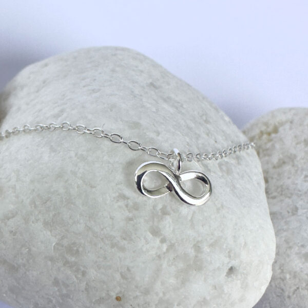 Close up of a silver anklet with an infinity charm.