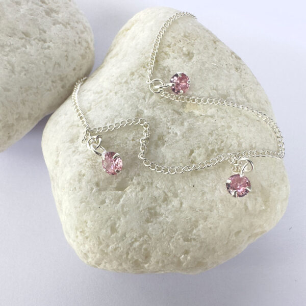 Silver anklet with three pink gemstones.