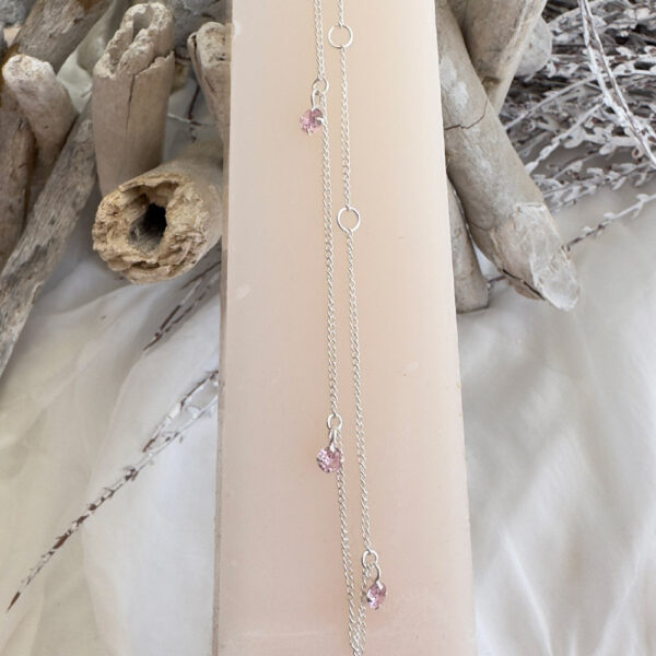 Silver anklet with three pink cubic zirconia gems hanging off around the chain.
