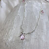Passionate pink coloured gemstones positioned around a sterling silver ankle bracelet, on top of a white crystal.