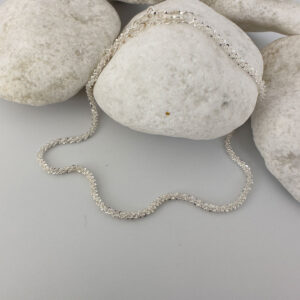 A simple sparkly ankle bracelet on a white rock.