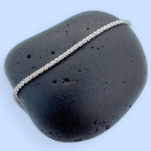 A simple sparkly ankle bracelet on a black rock.