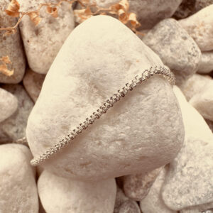 Simple sparkley silver anklet on a white rock.