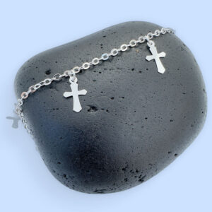 Silver anklet with three silver crosses equally spaced around the chain on a black rock.