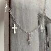 Gothic style silver anklet with five crosses around the chain, hanging off white washed wood.