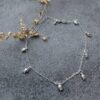 Sterling silver anklet with seven small tulip flower shaped charms in equal distance around the ankle chain.