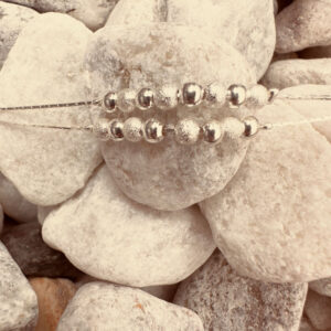 Double chain silver ankle bracelet with eight balls on each of the chains, alternating shiny silver then rough frosted silver.