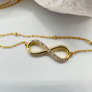 Stunning double chain gold anklet with an infinity charm with fifteen white gemstones along half of it