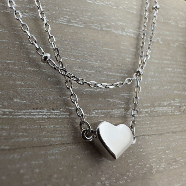 Simple sterling silver heart charm on a plain silver anklet.