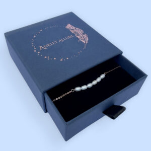 Rose gold anklet with six freshwater pearls presented in a dark blue Anklet Allure gift box.
