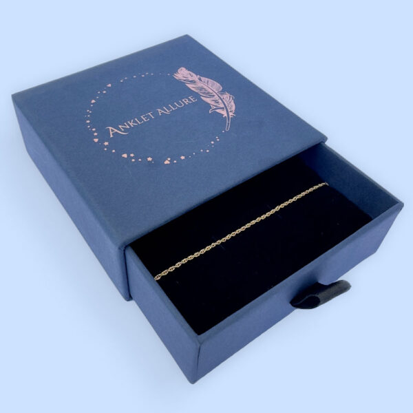 Dainty gold simple ankle bracelet presented in a dark blue Anklet Allure gift box.