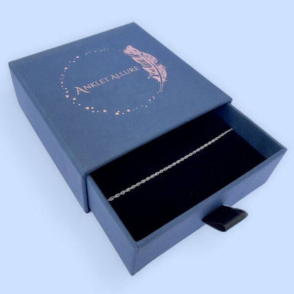 Plain silver ankle bracelet presented in a dark blue Anklet Allure gift box.