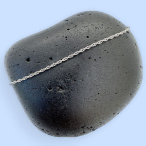 Plain silver chain displayed on a black rock.