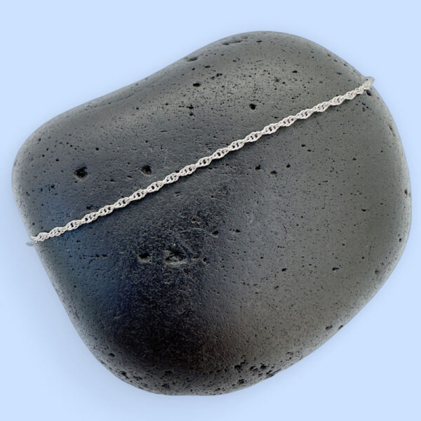 Plain silver chain displayed on a black rock.