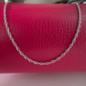 Chic simple silver anklet draped over a red purse.